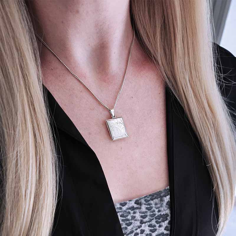 Person wearing a silver necklace with a pendant