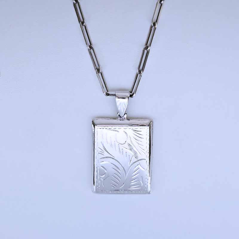 Silver necklace with a rectangular pendant on a light blue background
