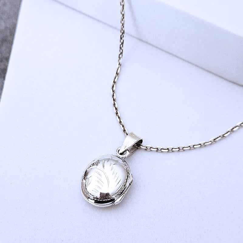 Silver necklace with a round pendant on a light gray background