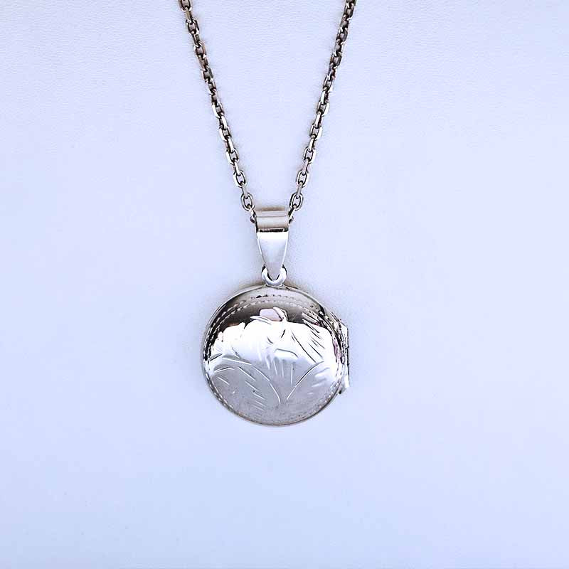 Silver locket necklace on a light blue background