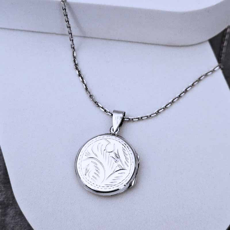 Silver necklace with a round pendant on a light gray background
