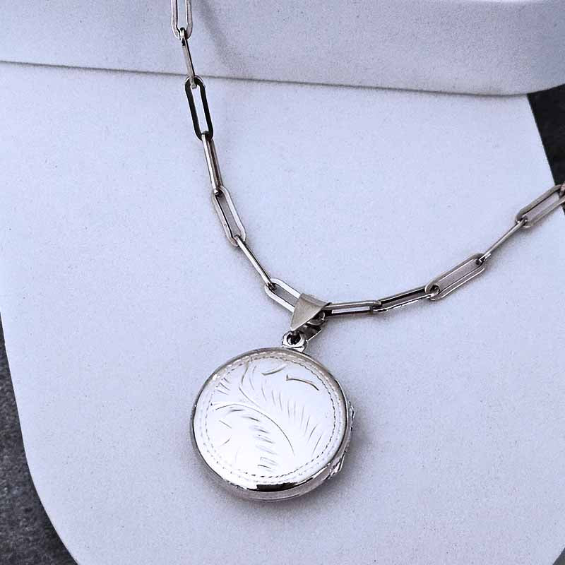 Silver necklace with a round pendant on a light gray background
