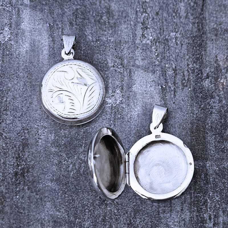 Two silver pendants on a textured gray surface