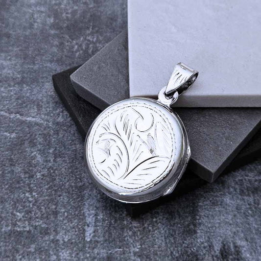 Silver pendant with floral design on a gray stone surface