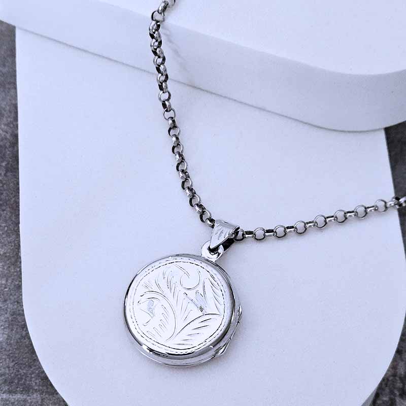 Silver necklace with a round pendant on a white background