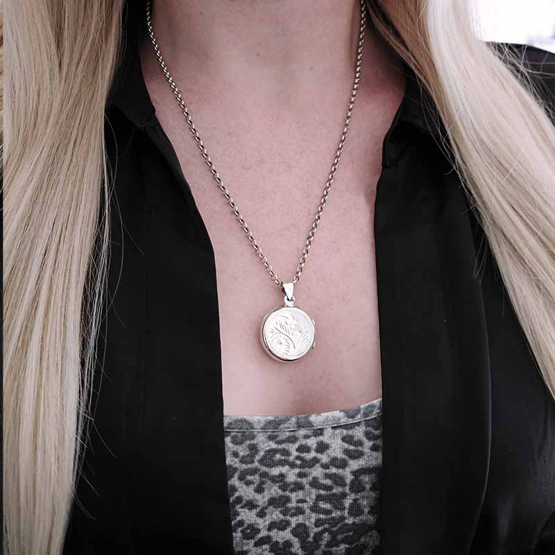 Person wearing a silver necklace with a round pendant