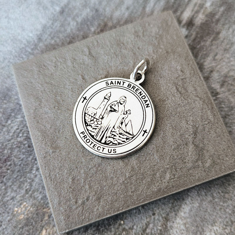 Silver Saint Brendan pendant on a textured stone surface