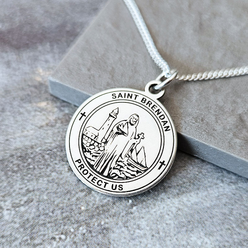Silver Saint Brendan pendant on a chain against a gray background