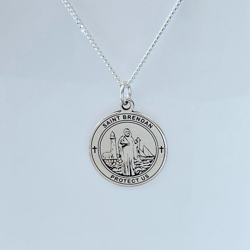 Silver necklace with a round pendant featuring an image of a saint and text on a light gray background