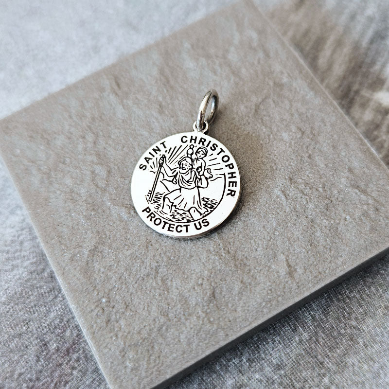 Silver Saint Christopher pendant on a stone surface