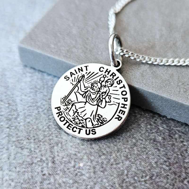 Silver Saint Christopher necklace on a textured surface