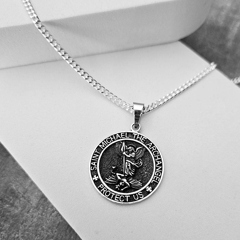 Silver necklace with a Saint Michael pendant on a white surface