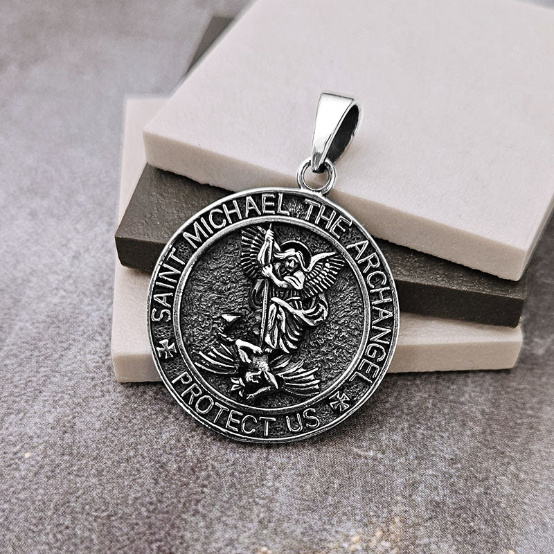 Silver pendant with 'Saint Michael the Archangel' engraving on a stone surface