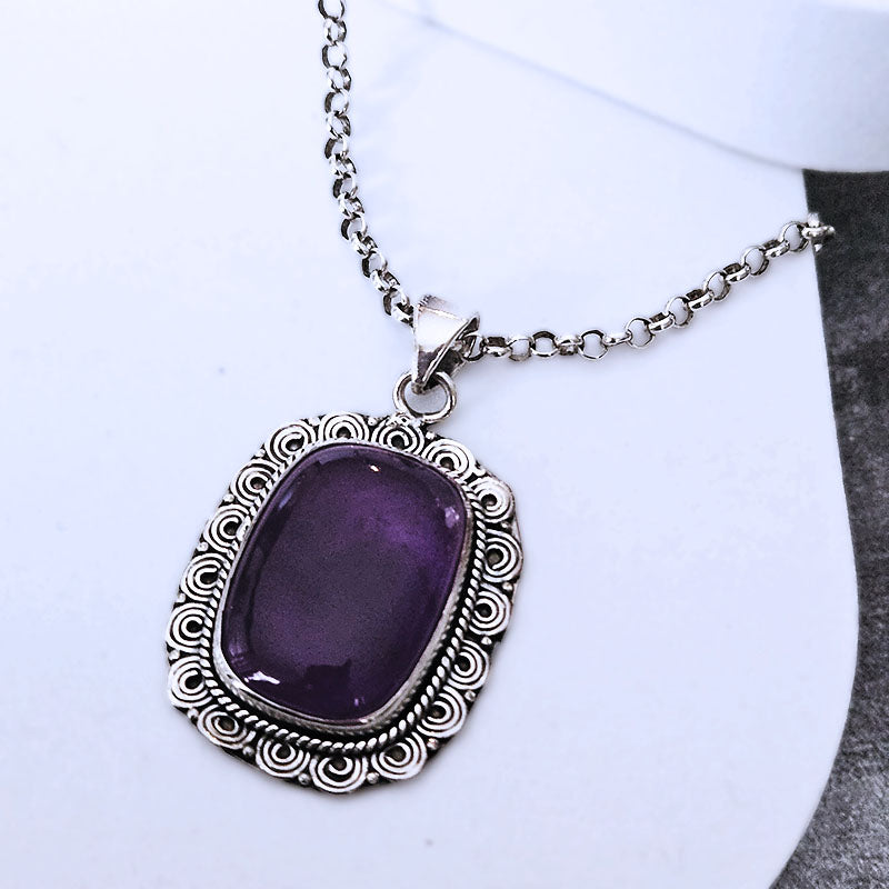 Purple Amethyst gemstone necklace with silver chain on a white background