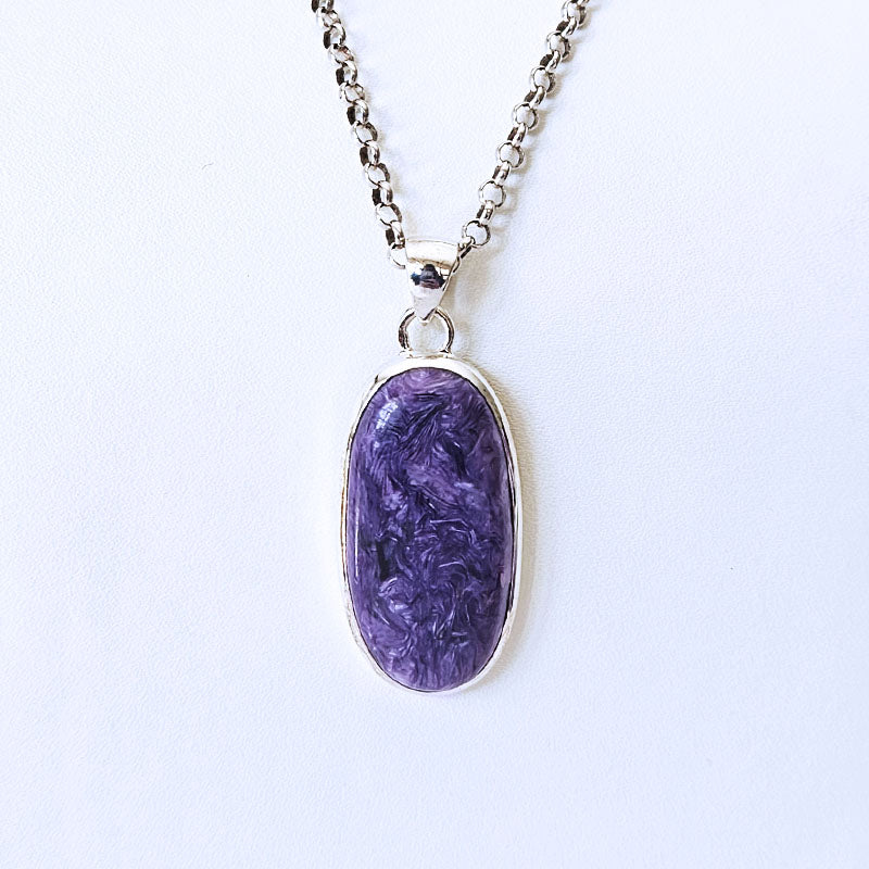 An oval purple stone pendant necklace with a silver bezel and matching silver chain, shown against a plain white background.
