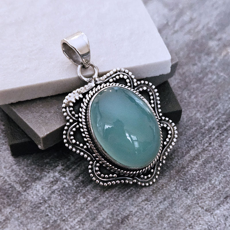 Silver pendant with a blue stone on a gray surface