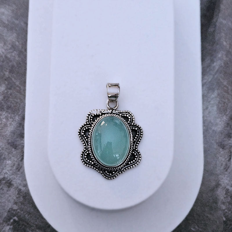 Chelcedony pendant with silver decorative frame on a white oval background