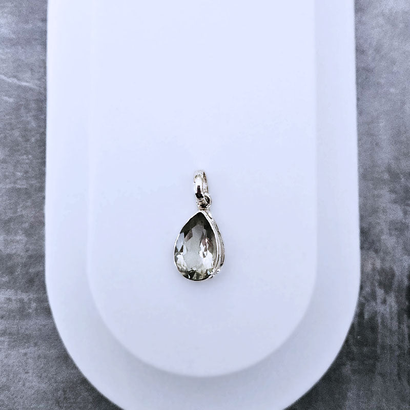 Teardrop-shaped pendant on a white stand with a gray background