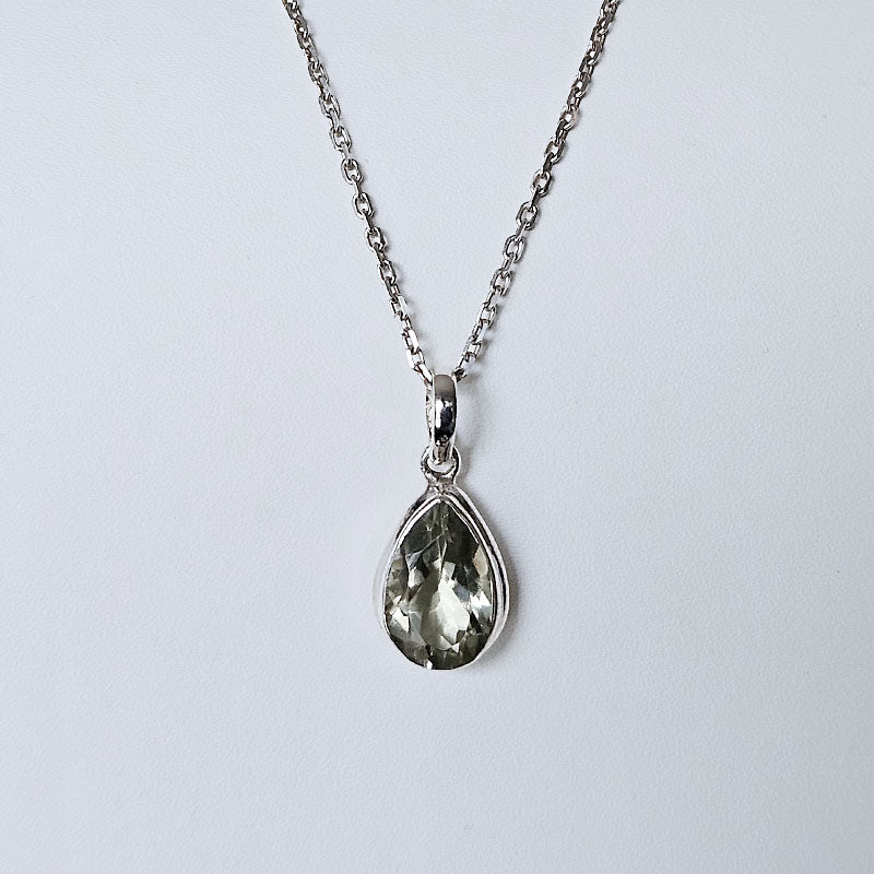Teardrop-shaped pendant on a chain against a light gray background