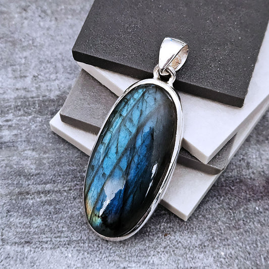 Labradorite pendant with silver frame on a textured surface