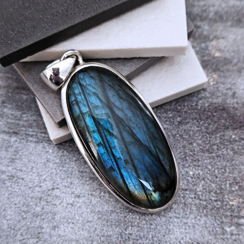 Labradorite pendant with silver setting on a textured surface