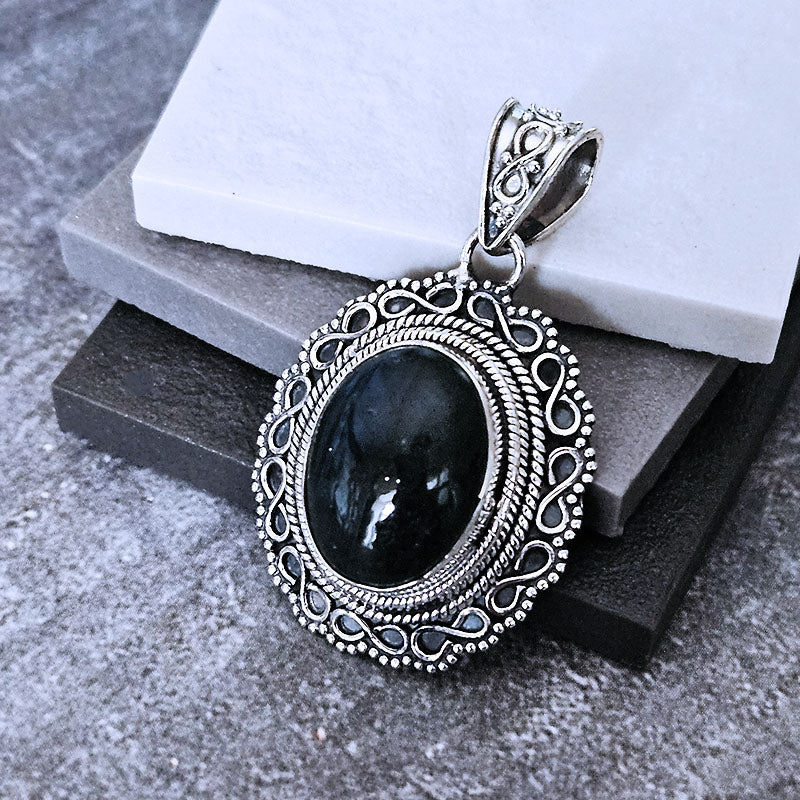 Silver pendant with Labradorite stone on a gray surface