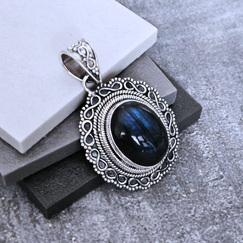 Silver pendant with a blue Labradorite  stone on a gray surface