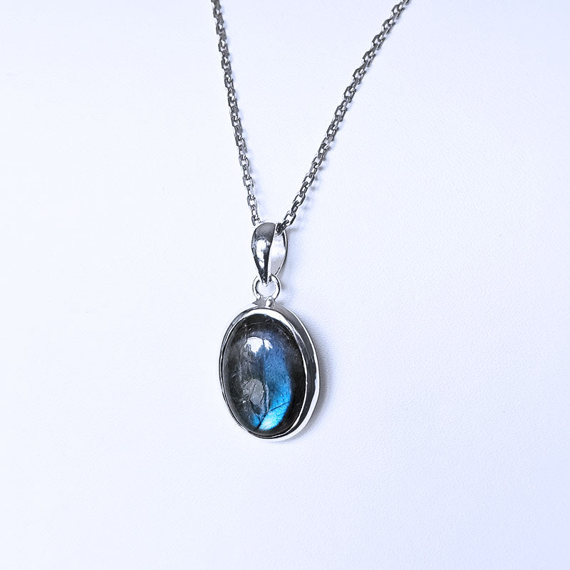 Silver pendant with blue gemstone on a white background