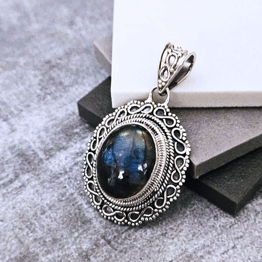 Silver pendant with a blue stone on a gray surface