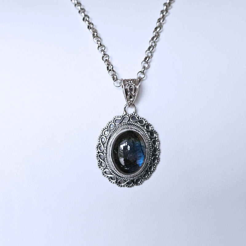 Silver necklace with a pendant featuring a blue gemstone on a white background