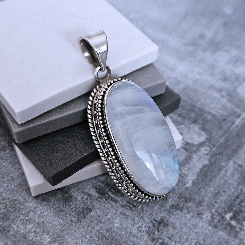 Silver pendant with a large stone on a textured surface