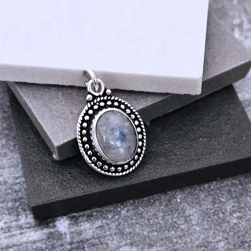 Silver pendant with a stone on a gray surface