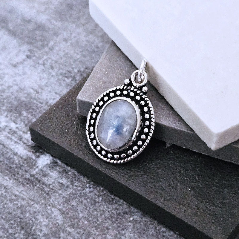 Silver moonstone pendant with a stone on a gray surface