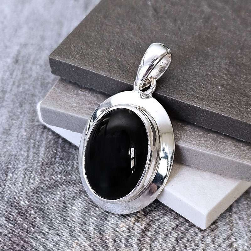 Silver pendant with a black stone on a gray surface