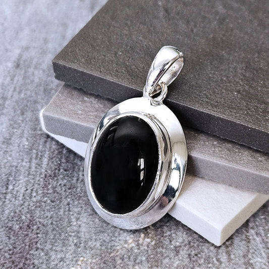 Silver pendant with a black stone on a gray surface