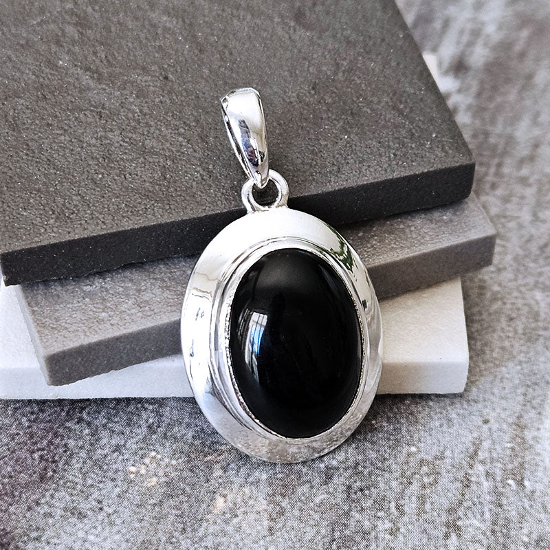 Silver pendant with a black stone on a textured surface