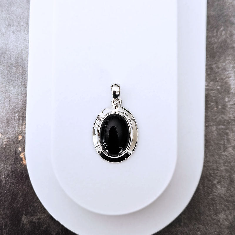 Silver pendant with a black stone on a white background