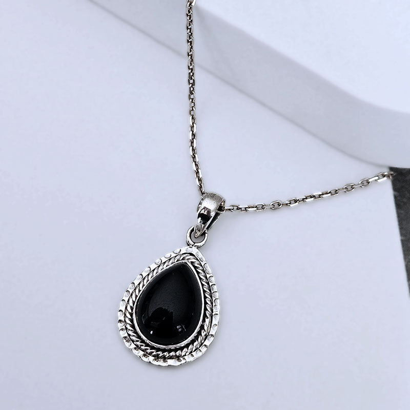 A silver teardrop pendant necklace with a textured rope-style border and a smooth black teardrop gemstone, displayed on a clean white surface.