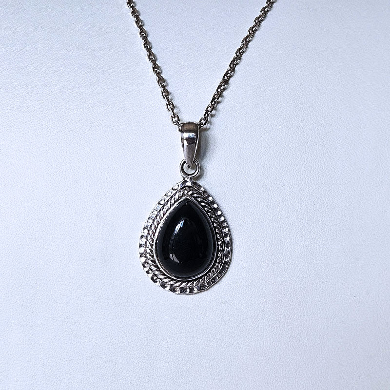 A silver teardrop pendant necklace with a dark, polished black stone in the center, set against a plain light gray background.