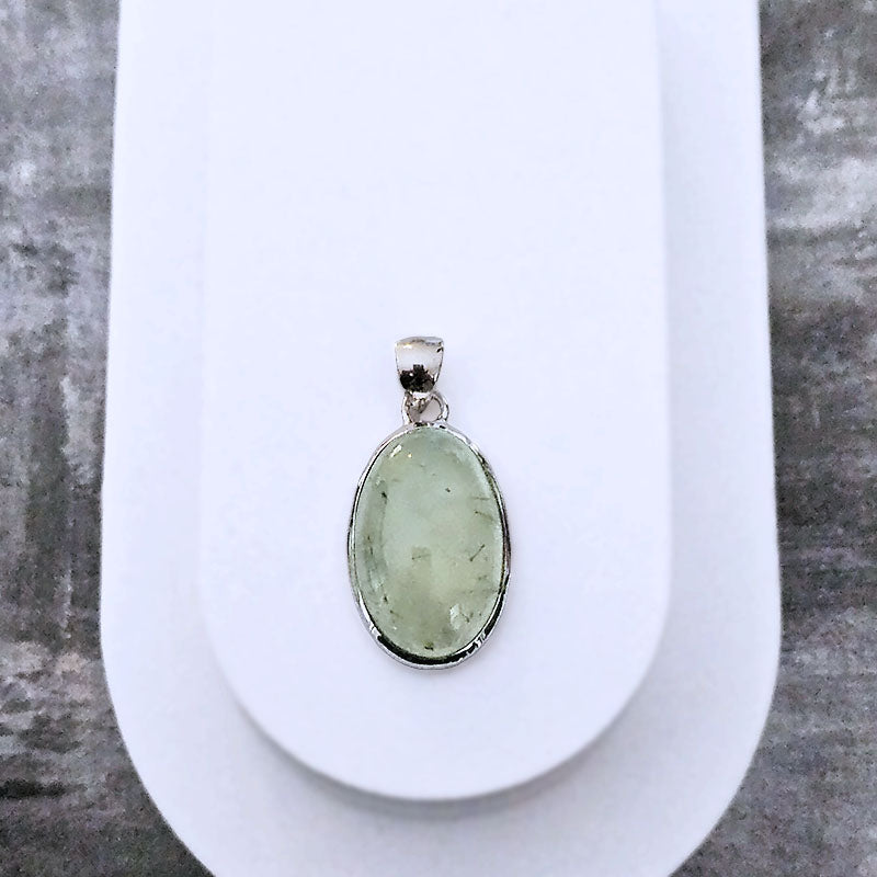 Green Prehnite pendant on a white oval stand with a gray background