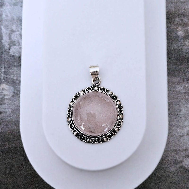 Silver pendant with a pink stone on a white background