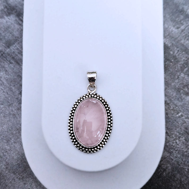 Pink stone pendant with silver frame on a white plate