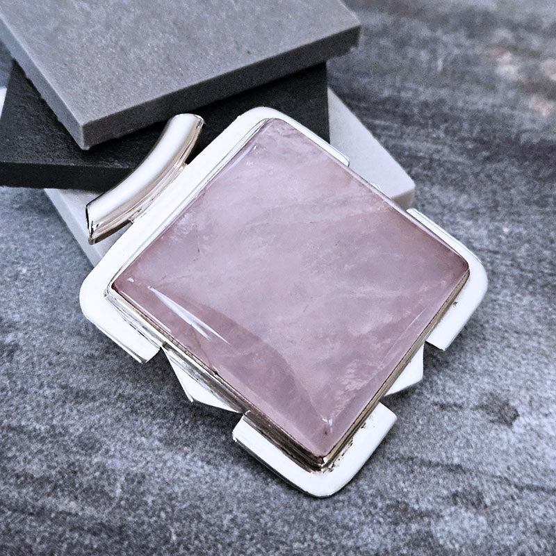 Pink stone in a silver frame on a textured gray surface