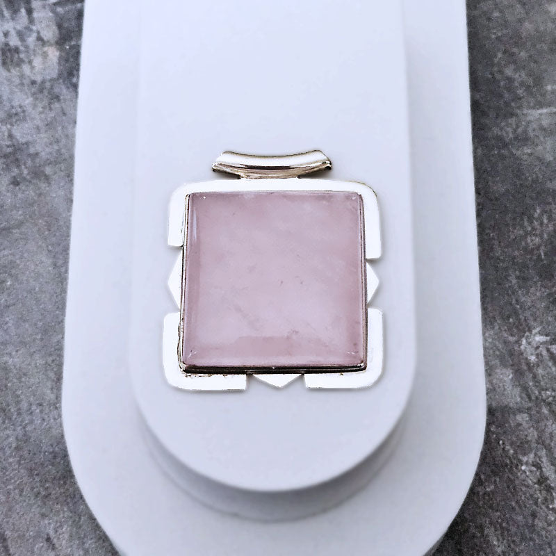 Pink stone pendant on a white stand with a gray background