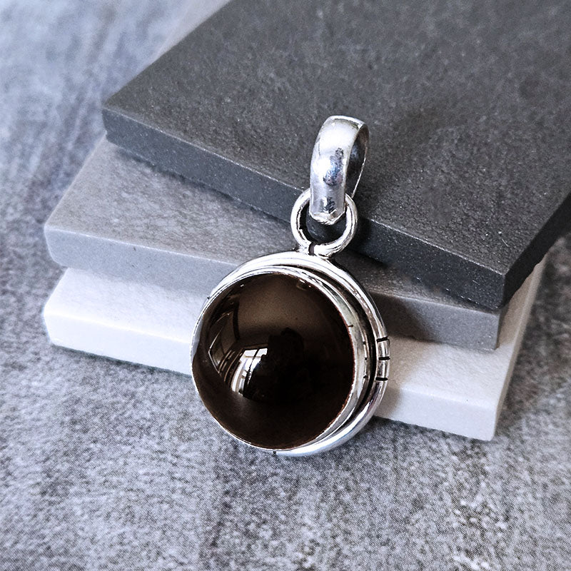 Silver pendant with a dark stone on a gray surface