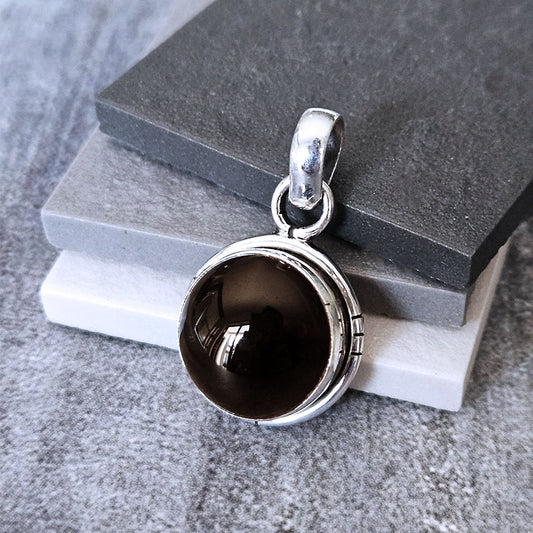 Silver pendant with a dark stone on a gray surface