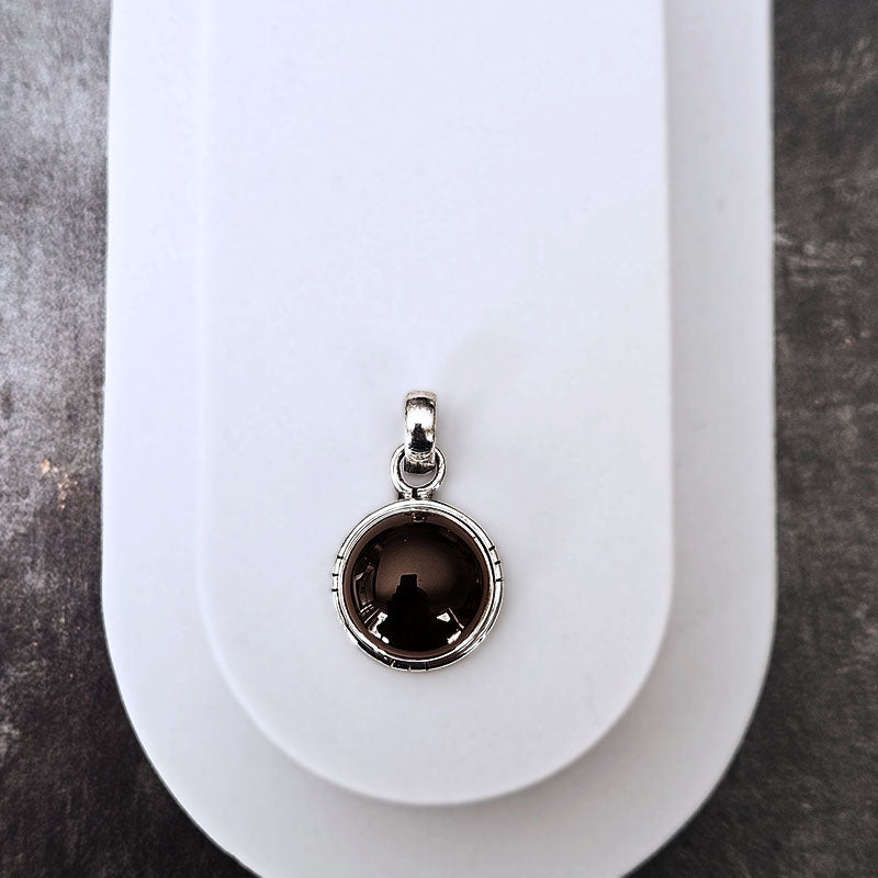 Silver pendant with a dark gemstone on a white background
