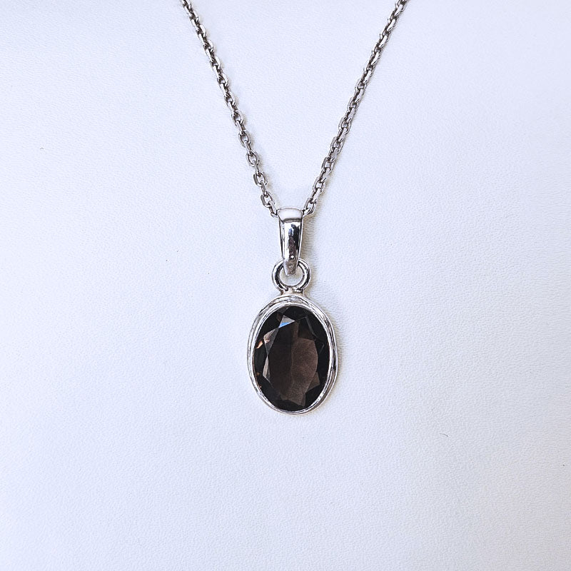 A silver chain necklace with an oval dark brown faceted gemstone pendant, displayed against a plain white background.