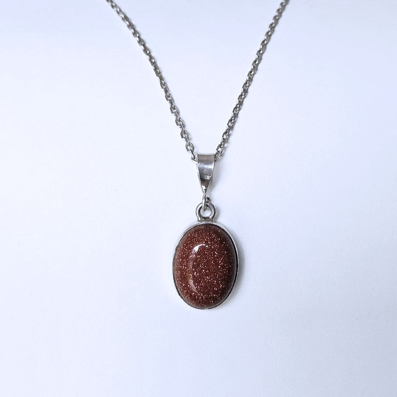 Necklace with a brown oval Sunstone pendant on a light blue backgroundTONE 