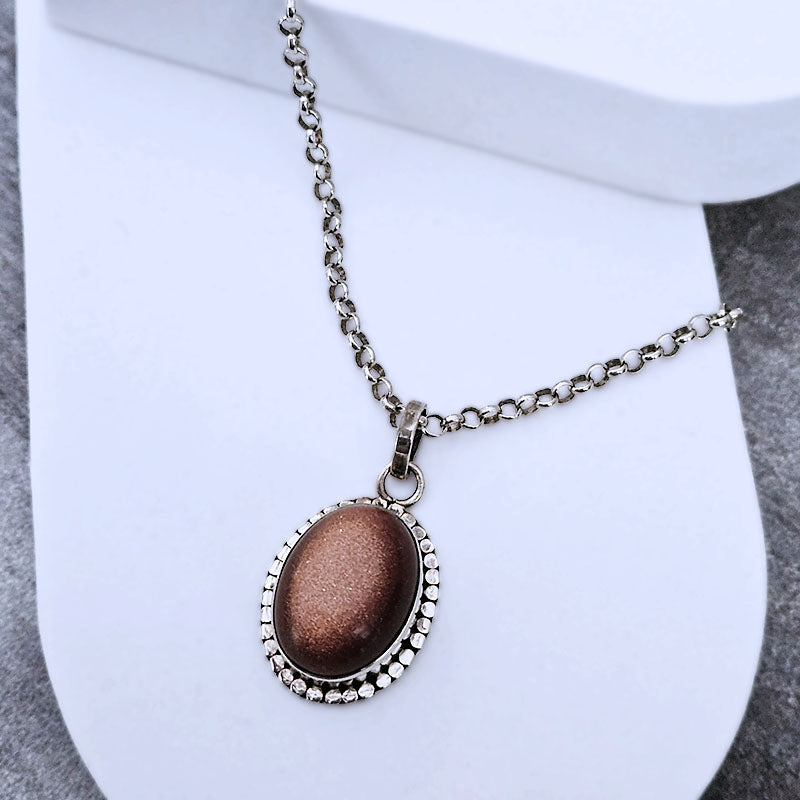 Necklace with a sunstone pendant on a white stand